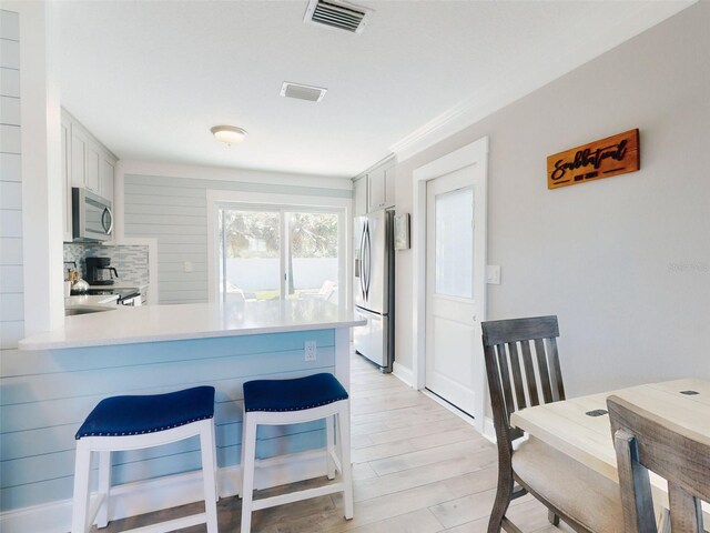 16 Hillside Dr, New Smyrna Beach, FL 32169 - kitchen with tasteful backsplash, light countertops, light wood-style floors, visible vents, and appliances with stainless steel finishes