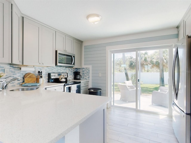 16 Hillside Dr, New Smyrna Beach, FL 32169 - kitchen with tasteful backsplash, light stone counters, gray cabinetry, stainless steel appliances, and a sink