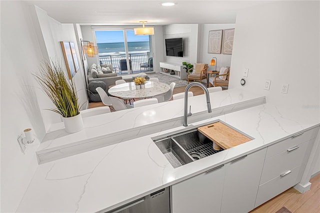 705 N Atlantic Ave Unit 4030, New Smyrna Beach, FL 32169 - kitchen with light wood finished floors, a sink, light stone counters, white cabinetry, and open floor plan
