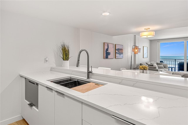 705 N Atlantic Ave Unit 4030, New Smyrna Beach, FL 32169 - kitchen featuring white cabinets, a sink, a water view, open floor plan, and light stone countertops