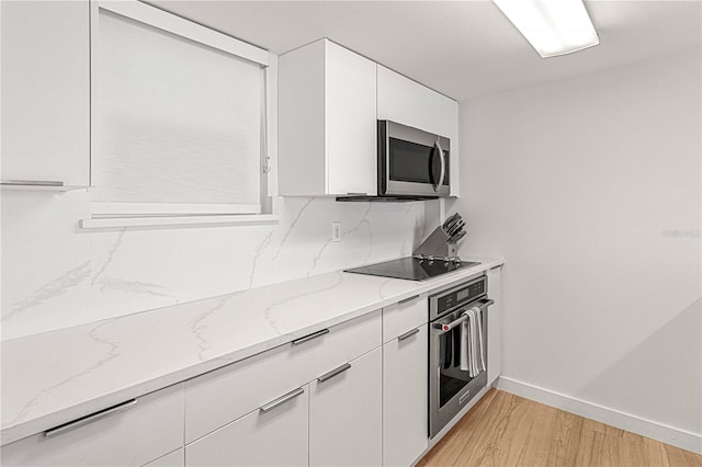 705 N Atlantic Ave Unit 4030, New Smyrna Beach, FL 32169 - kitchen with baseboards, light stone countertops, appliances with stainless steel finishes, light wood finished floors, and white cabinetry