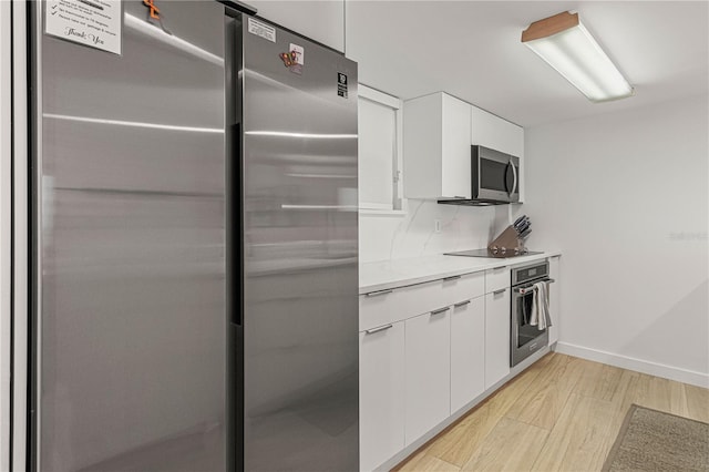 705 N Atlantic Ave Unit 4030, New Smyrna Beach, FL 32169 - kitchen featuring modern cabinets, stainless steel appliances, light wood-style floors, white cabinetry, and baseboards