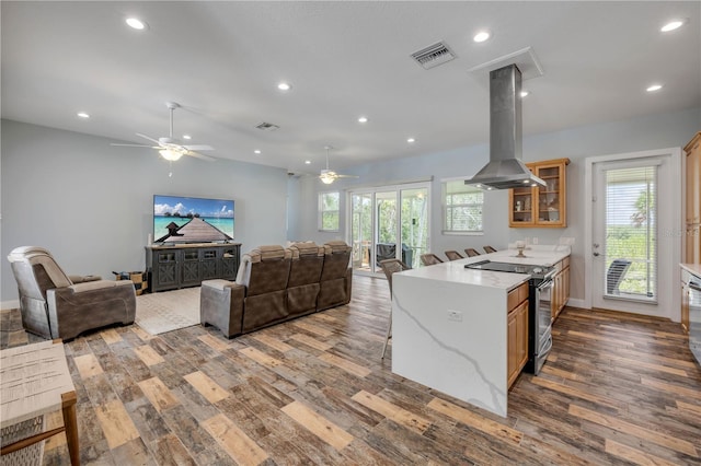 kitchen with island range hood, electric stove, visible vents, and open floor plan