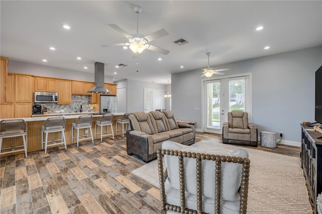 living area with light wood-style flooring, a ceiling fan, visible vents, and recessed lighting