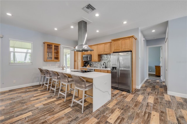 kitchen with island range hood, visible vents, a breakfast bar area, stainless steel appliances, and wood finished floors