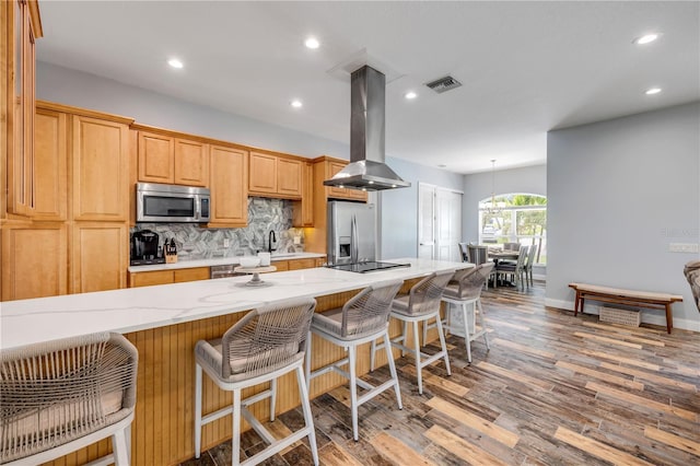 kitchen featuring island range hood, backsplash, visible vents, stainless steel appliances, and wood finished floors