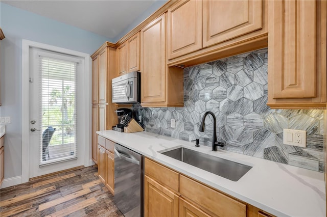 kitchen with dark wood-type flooring, tasteful backsplash, appliances with stainless steel finishes, light countertops, and a sink