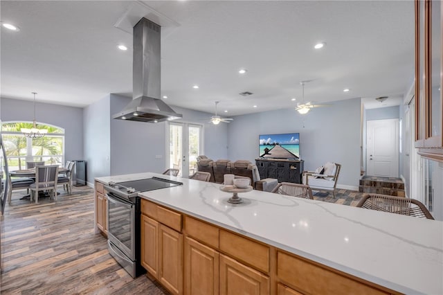 kitchen with ceiling fan with notable chandelier, wood finished floors, electric stove, open floor plan, and island range hood