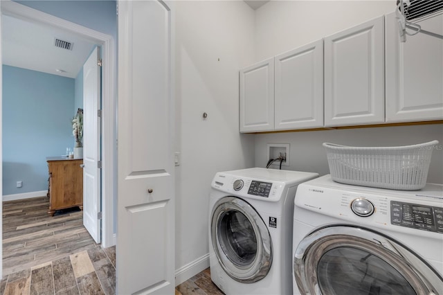 laundry area featuring cabinet space, visible vents, separate washer and dryer, and wood tiled floor