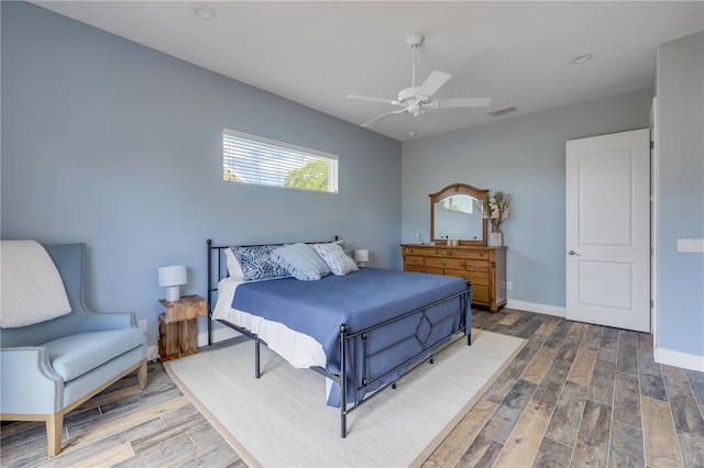 bedroom featuring visible vents, baseboards, a ceiling fan, and wood finished floors