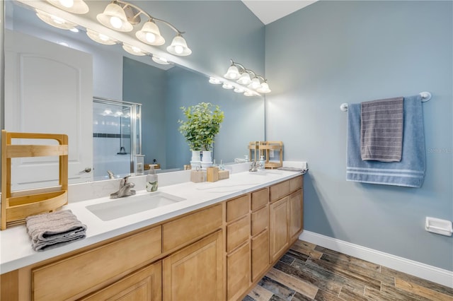 bathroom featuring double vanity, baseboards, a sink, and wood finished floors