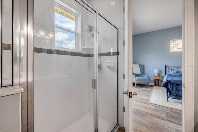 full bath featuring connected bathroom, a stall shower, wood finished floors, and a healthy amount of sunlight