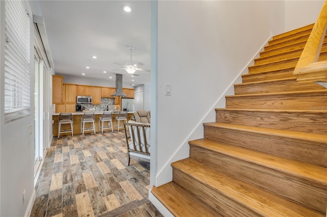 staircase with recessed lighting, a ceiling fan, and wood finished floors