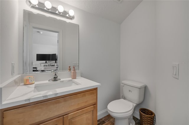 half bathroom featuring toilet, a textured ceiling, vanity, and baseboards