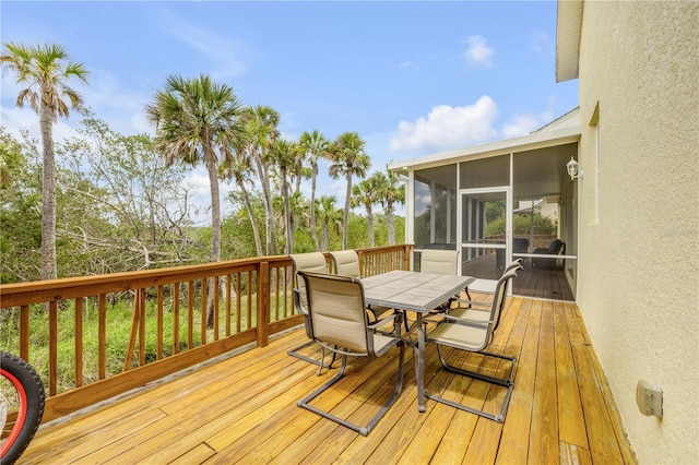 wooden terrace with outdoor dining area and a sunroom