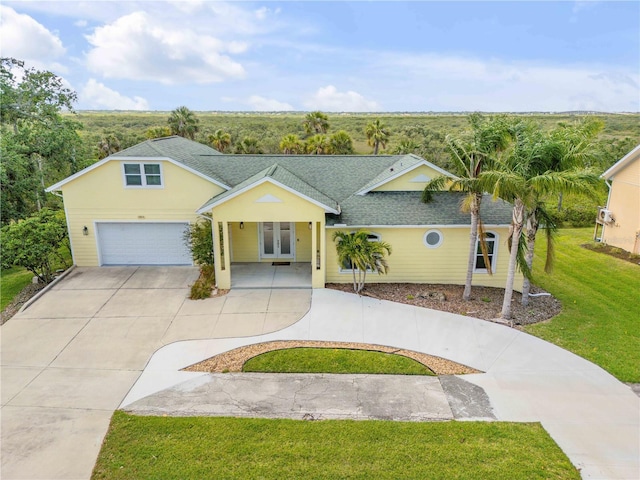 single story home with a garage, roof with shingles, a front yard, french doors, and concrete driveway