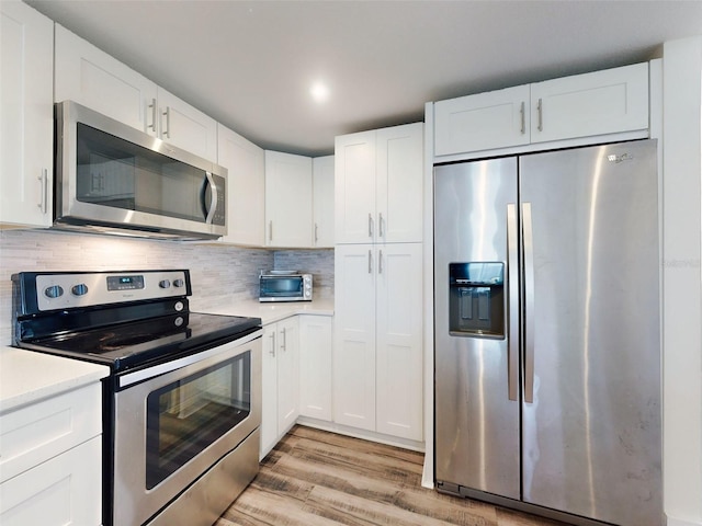 4752 S Atlantic Ave Unit 1, Ponce Inlet, FL 32127 - kitchen featuring appliances with stainless steel finishes, light countertops, light wood-style floors, and white cabinets