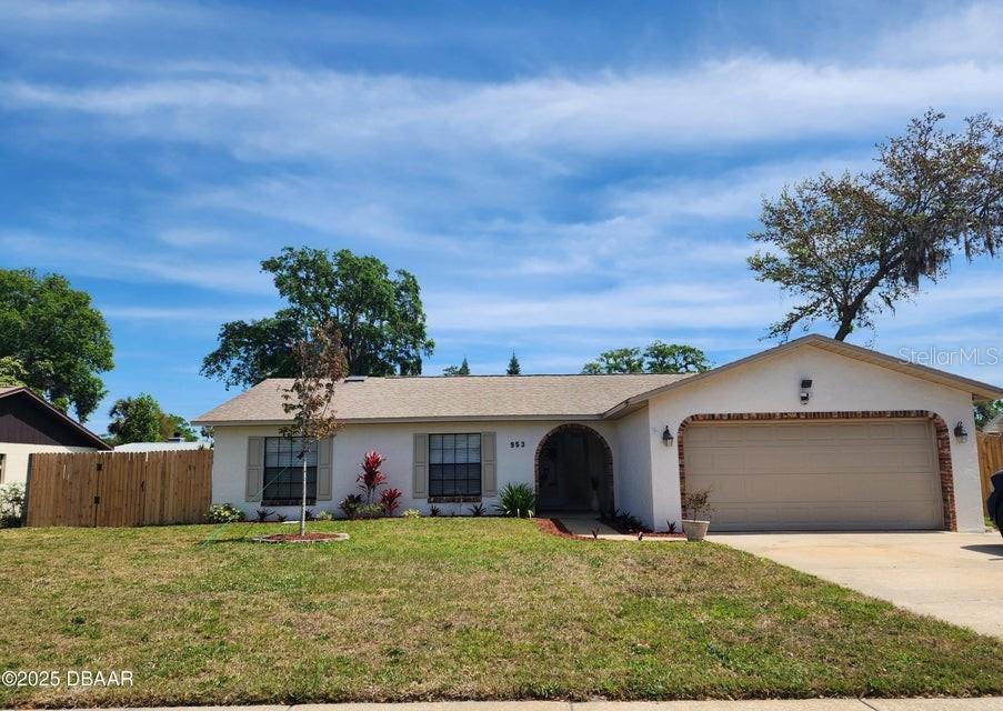 953 Sand Crest Dr, Port Orange, FL 32127 - single story home with concrete driveway, stucco siding, an attached garage, a front yard, and fence
