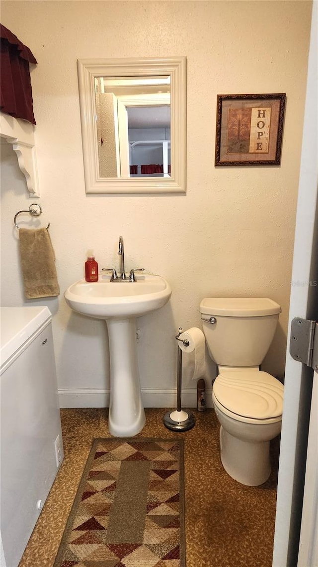 bathroom with baseboards, a sink, and toilet