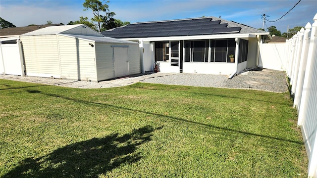 rear view of property featuring a sunroom, a shed, a yard, a fenced backyard, and an outdoor structure