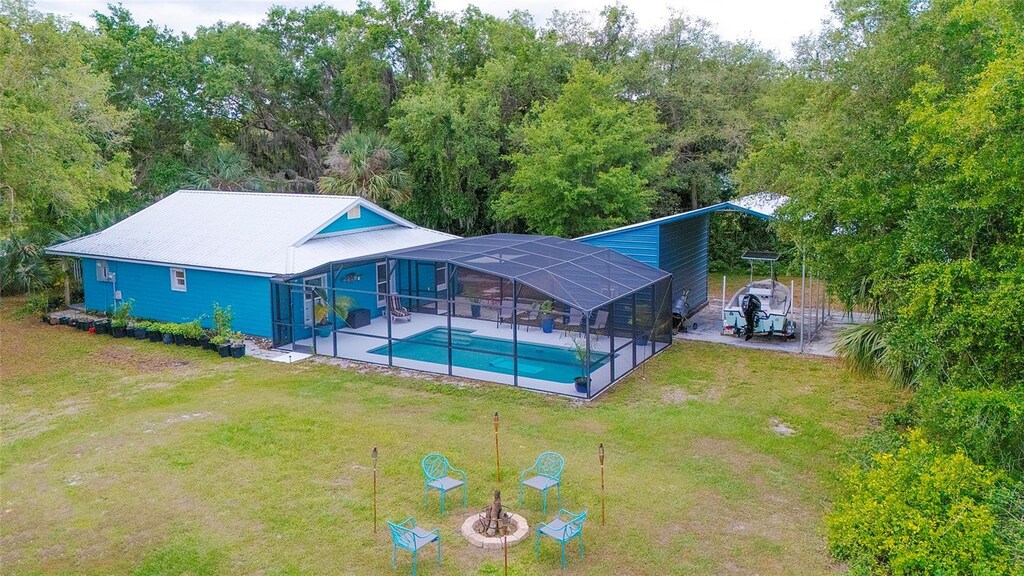 outdoor pool with glass enclosure, a patio, and a lawn
