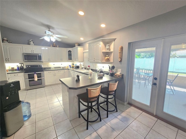 2530 Tamarind Dr, Edgewater, FL 32141 - kitchen with stainless steel appliances, vaulted ceiling, a peninsula, dark countertops, and white cabinets