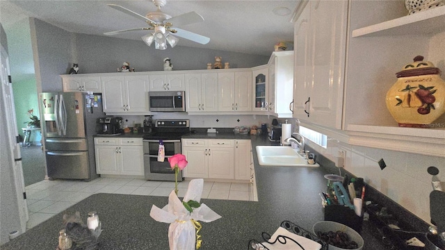 2530 Tamarind Dr, Edgewater, FL 32141 - kitchen with stainless steel appliances, a sink, vaulted ceiling, dark countertops, and white cabinetry
