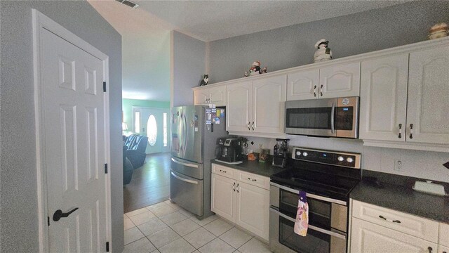 2530 Tamarind Dr, Edgewater, FL 32141 - kitchen with appliances with stainless steel finishes, dark countertops, white cabinets, and light tile patterned floors