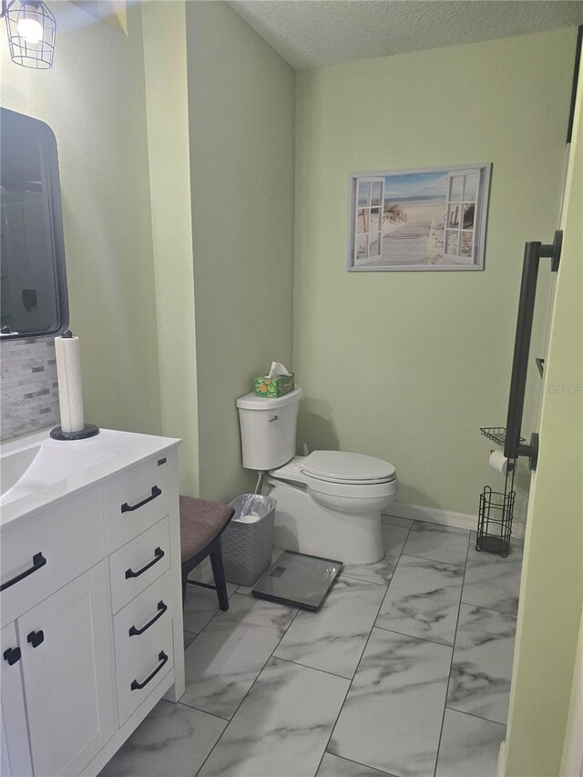 2530 Tamarind Dr, Edgewater, FL 32141 - bathroom with marble finish floors, toilet, vanity, baseboards, and a textured ceiling
