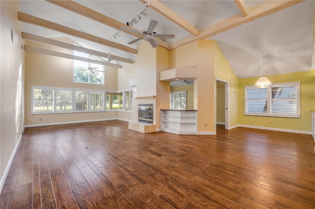 606 Saint Andrews Blvd, New Smyrna Beach, FL 32168 - unfurnished living room featuring ceiling fan with notable chandelier, a tiled fireplace, beam ceiling, and dark wood-type flooring
