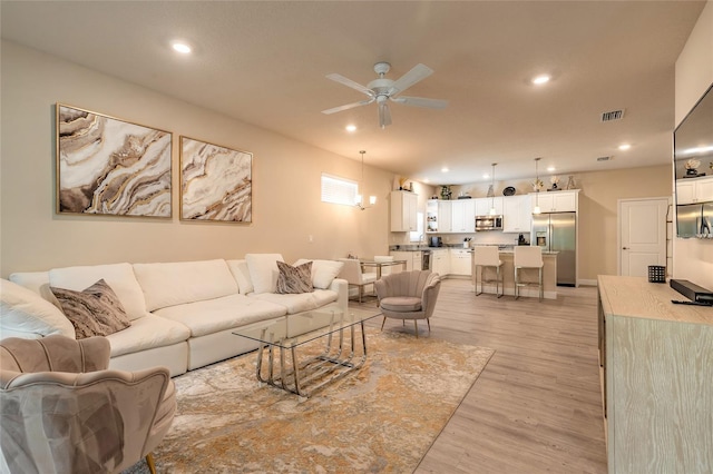living room featuring recessed lighting, light wood-style flooring, visible vents, and a ceiling fan