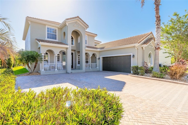 495 Venetian Villa Dr, New Smyrna Beach, FL 32168 - mediterranean / spanish house featuring stucco siding, decorative driveway, an attached garage, a porch, and a tiled roof
