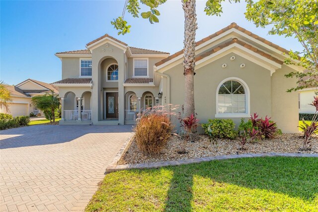 495 Venetian Villa Dr, New Smyrna Beach, FL 32168 - mediterranean / spanish-style home with stucco siding, french doors, decorative driveway, a tile roof, and covered porch