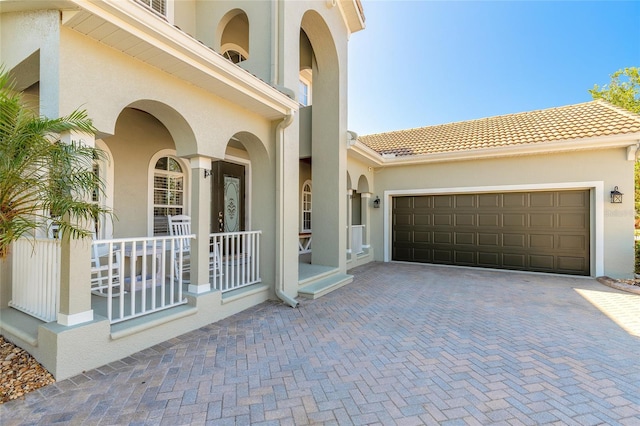 495 Venetian Villa Dr, New Smyrna Beach, FL 32168 - property entrance with covered porch, stucco siding, driveway, and a tile roof