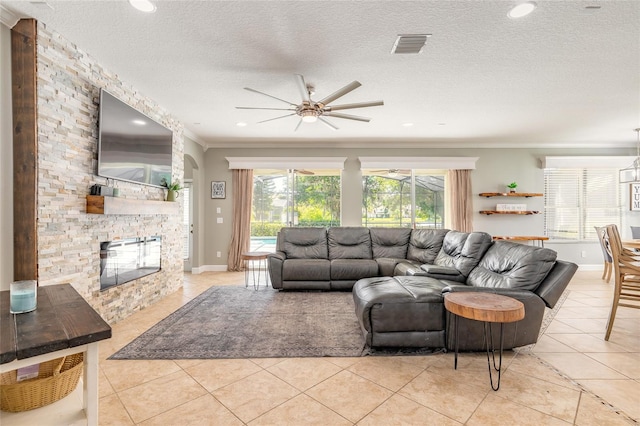 495 Venetian Villa Dr, New Smyrna Beach, FL 32168 - living area featuring ornamental molding, a fireplace, a ceiling fan, light tile patterned flooring, and visible vents