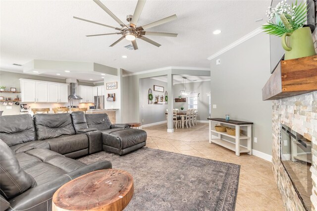 495 Venetian Villa Dr, New Smyrna Beach, FL 32168 - living room with a stone fireplace, a ceiling fan, crown molding, and light tile patterned flooring