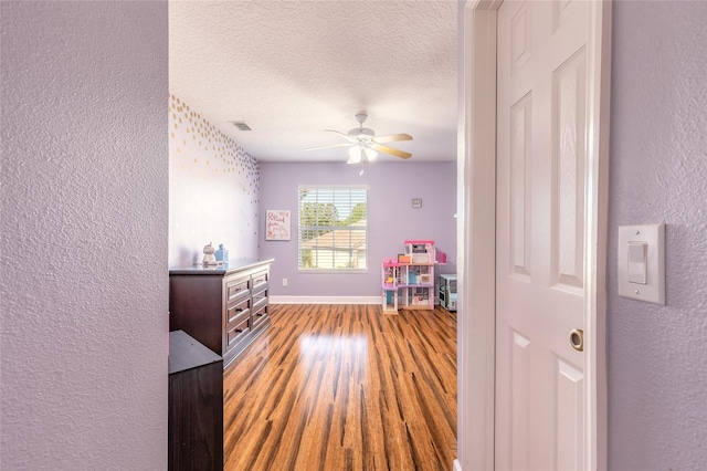 495 Venetian Villa Dr, New Smyrna Beach, FL 32168 - recreation room featuring a ceiling fan, wood finished floors, a textured wall, and a textured ceiling