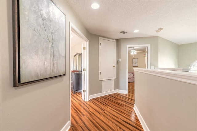 495 Venetian Villa Dr, New Smyrna Beach, FL 32168 - hallway featuring visible vents, baseboards, wood finished floors, and a textured ceiling