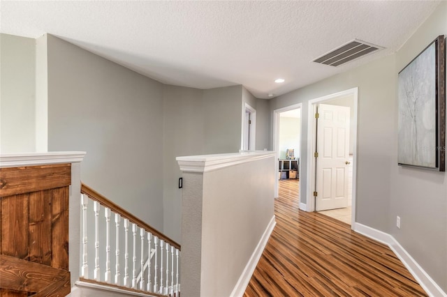 495 Venetian Villa Dr, New Smyrna Beach, FL 32168 - corridor featuring a textured ceiling, wood finished floors, visible vents, and an upstairs landing
