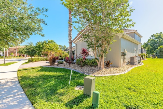 495 Venetian Villa Dr, New Smyrna Beach, FL 32168 - view of home's exterior with a yard, a tiled roof, central air condition unit, and stucco siding