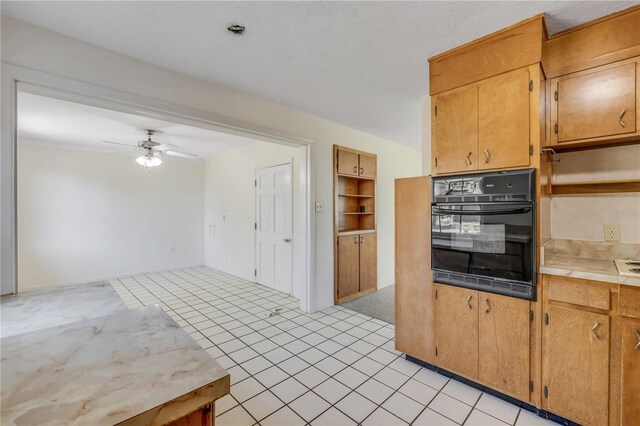 915 E 2nd Ave, New Smyrna Beach, FL 32169 - kitchen with light tile patterned floors, light countertops, a ceiling fan, and black oven