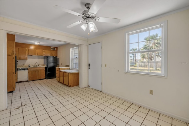 915 E 2nd Ave, New Smyrna Beach, FL 32169 - kitchen featuring brown cabinets, light countertops, freestanding refrigerator, and white dishwasher