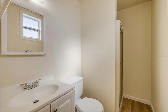 915 E 2nd Ave, New Smyrna Beach, FL 32169 - bathroom with vanity, baseboards, toilet, and wood finished floors