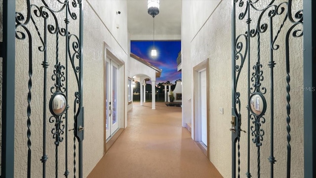 hallway with arched walkways, a high ceiling, and a textured wall