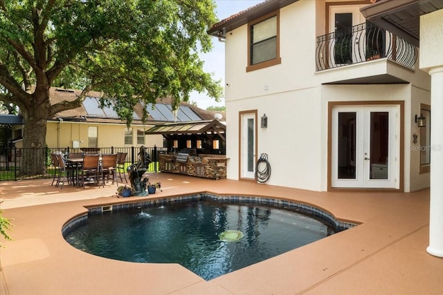 view of swimming pool featuring fence, a patio, french doors, an outdoor kitchen, and a fenced in pool