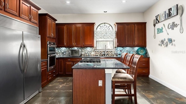 kitchen with decorative backsplash, a breakfast bar area, a kitchen island, appliances with stainless steel finishes, and a sink