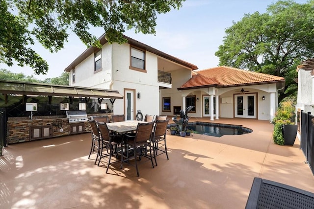 rear view of house featuring an outdoor kitchen, stucco siding, an outdoor pool, french doors, and a ceiling fan
