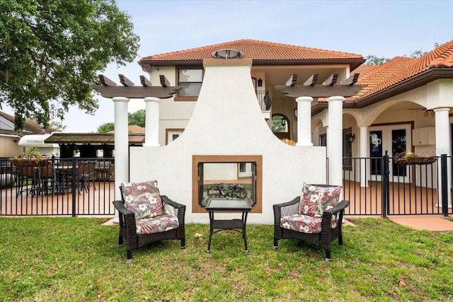 back of property featuring a lawn, fence, a tile roof, and stucco siding