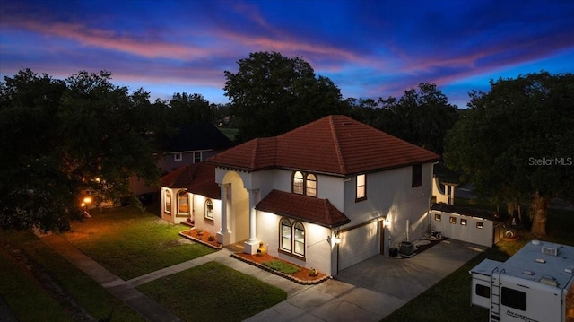 view of front of house with a garage, stucco siding, concrete driveway, a yard, and a tile roof