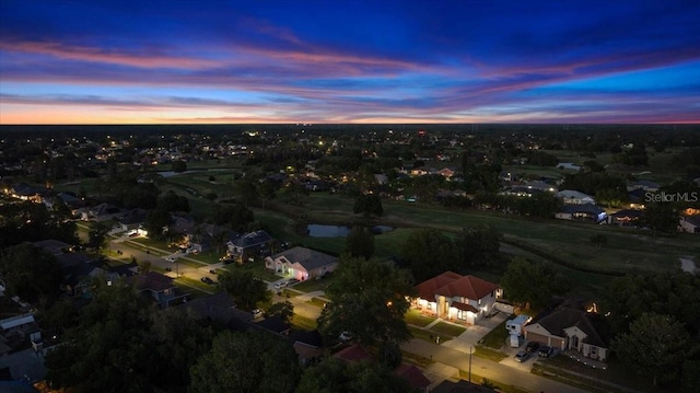 aerial view at dusk featuring a water view and a residential view